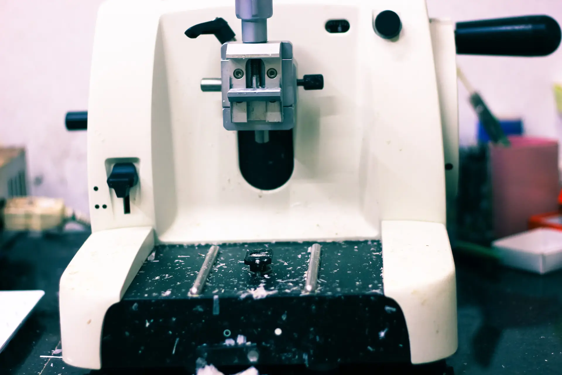 Front view of a rotary microtome showing the specimen holder, handwheel and paraffin shavings on the stage