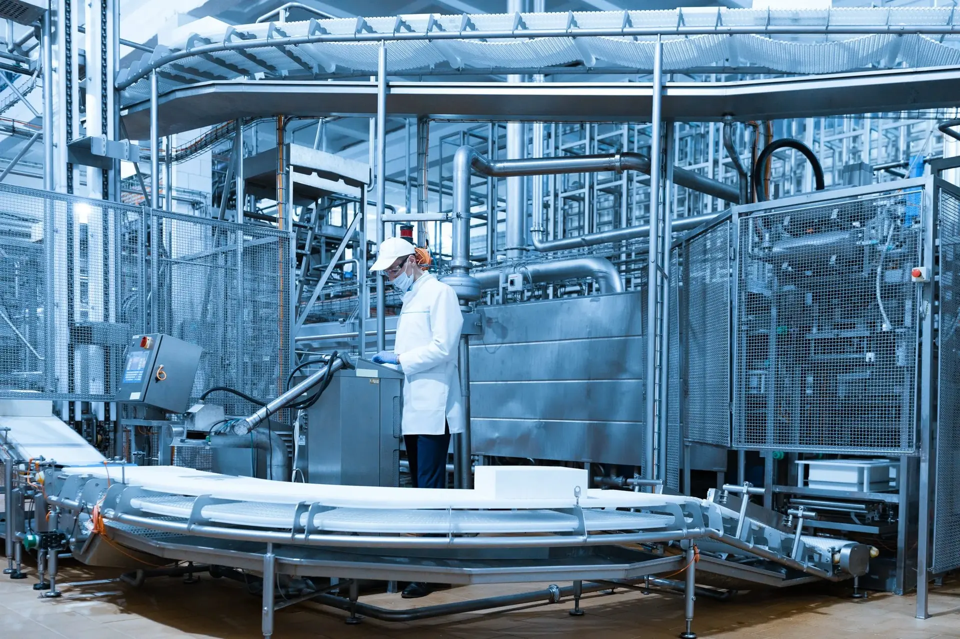 Technologist setting up a food production line beside a digital control screen