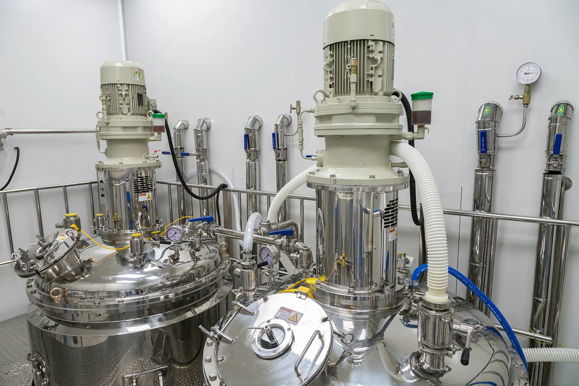Stainless steel processing vessels with motors and pressure gauges in a cleanroom laboratory