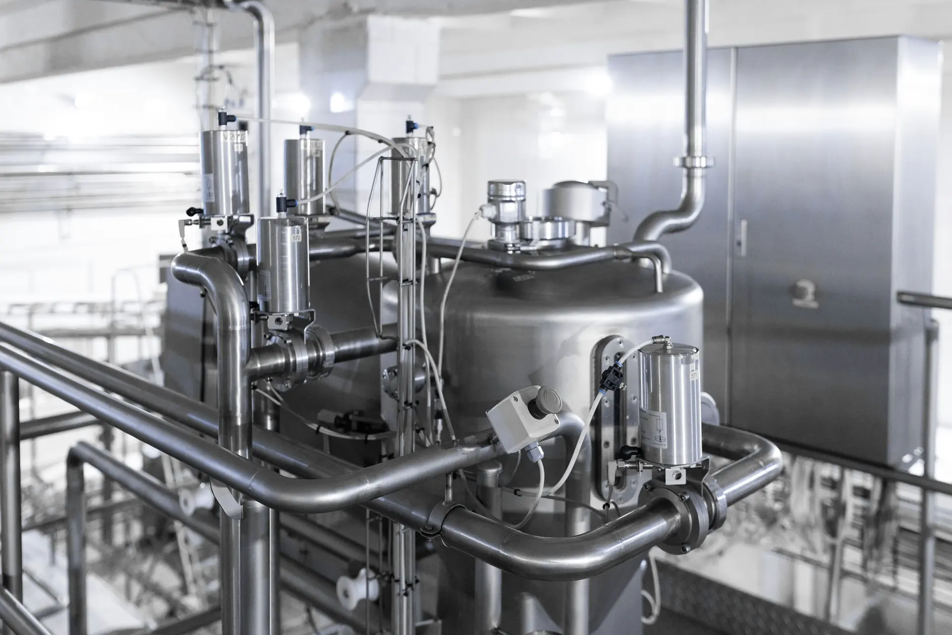 Stainless steel process tank with pneumatic valves and hygienic pipework in an industrial production plant