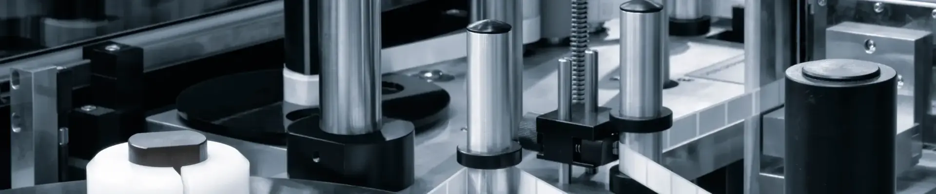 Black and white close-up of polished steel columns and components inside an automated production machine