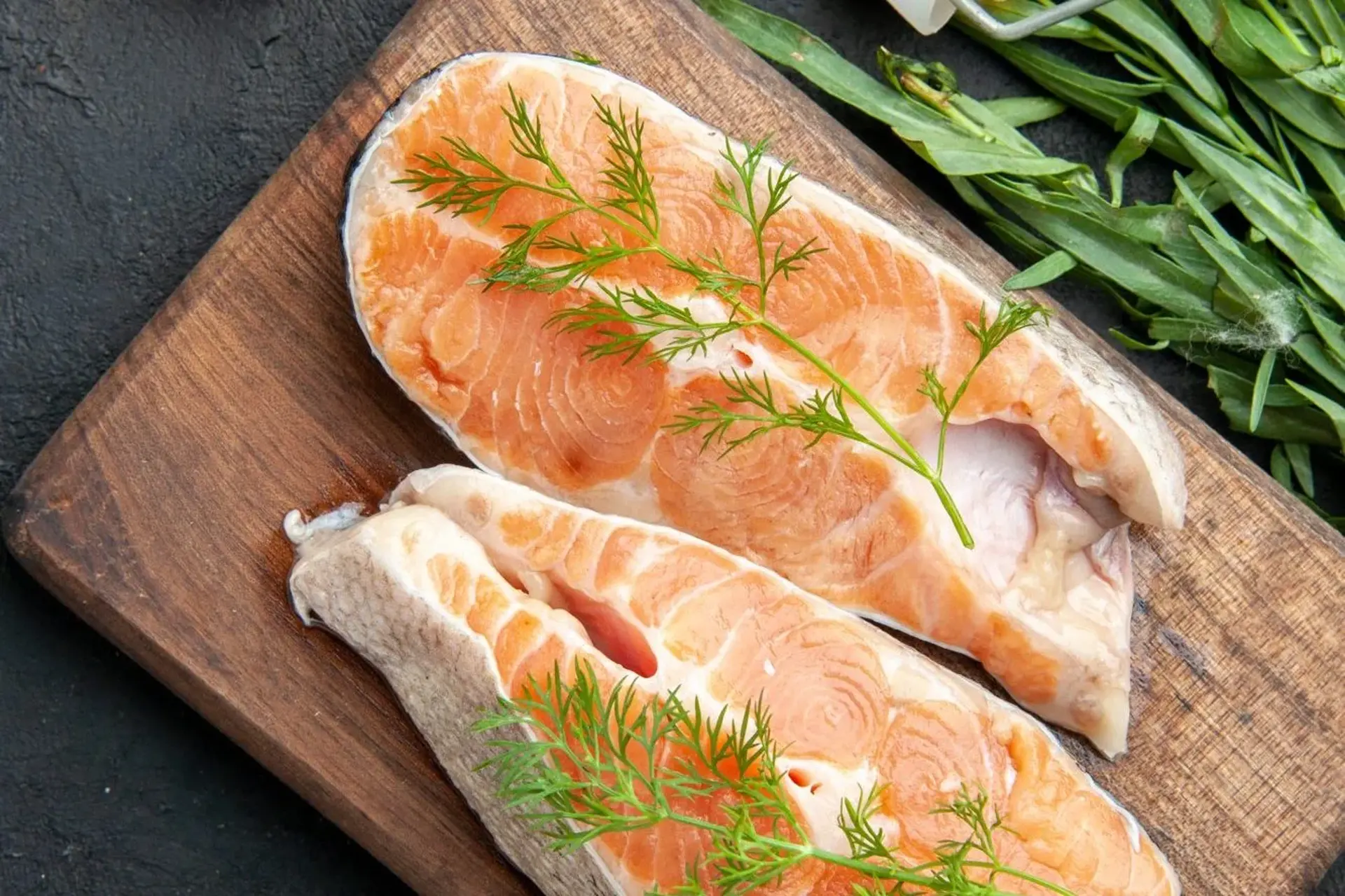 Whole salmon on a wooden cutting board with lemon slices